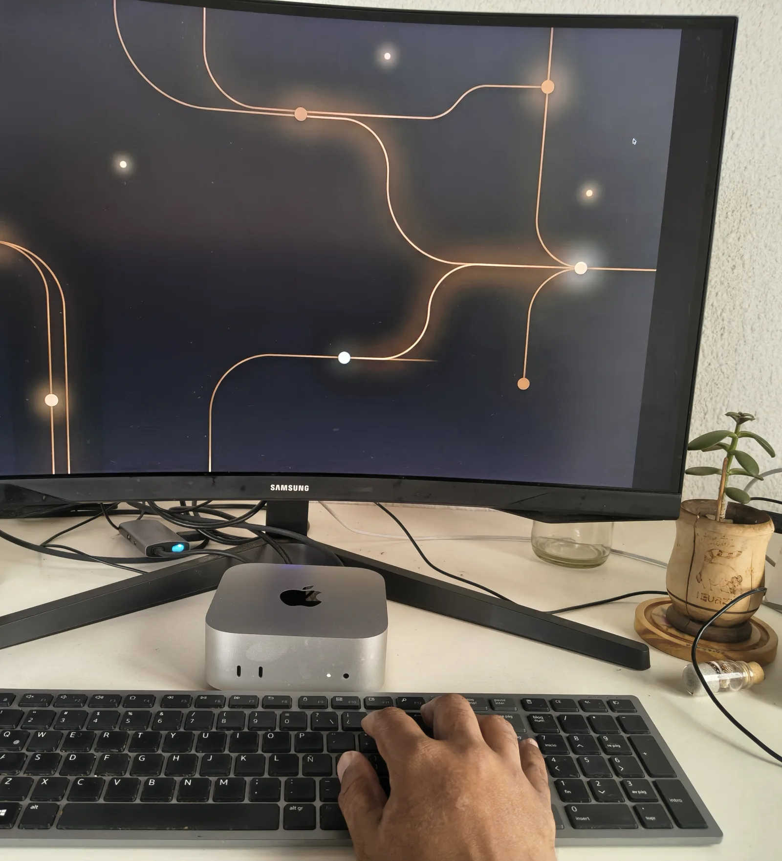Escritorio de trabajo: una mano sobre el teclado frente a un monitor curvo